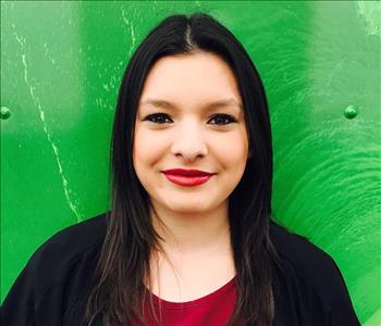 Female employee smiling in front of a green background 