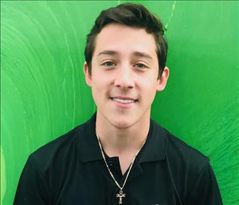 Male employee smiling in front of a green background 