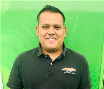 Male employee smiling in front of a green background 