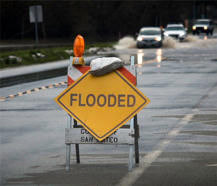 a street sign saying flooded over a flooded street