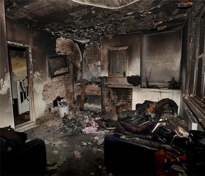 a fire damaged living room with soot covering everything and debris everywhere