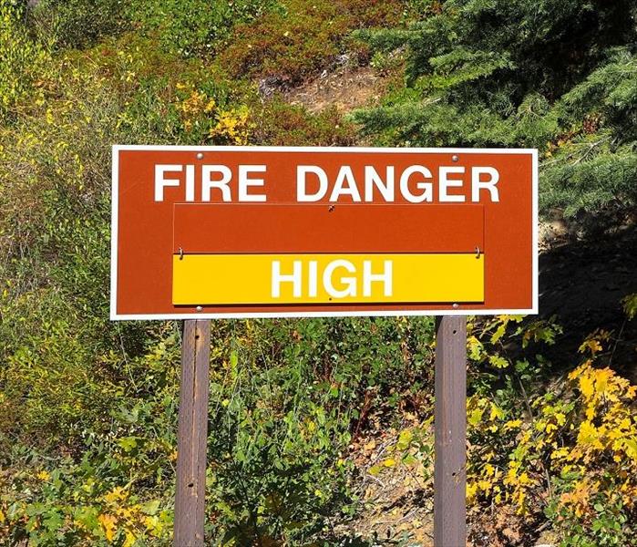 'fire danger' sign outside; wild, dry brush in background