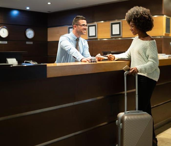 A man and woman standing at a hotel desk.