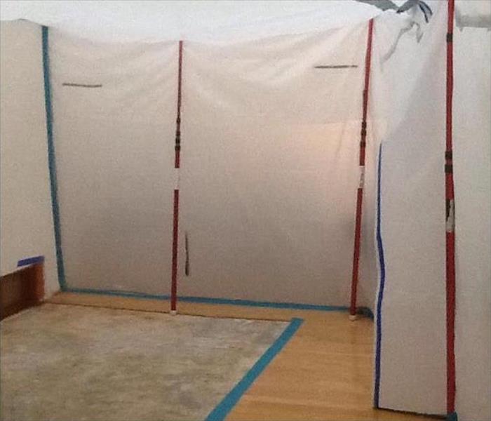 room with wood floors and plastic sheeting hung with blue and red tape
